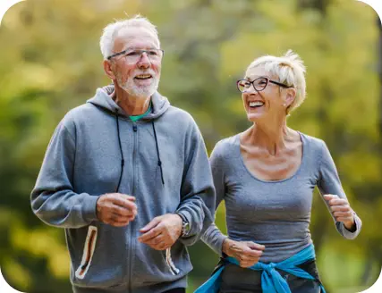 A middle-aged couple in activewear is walking briskly outside